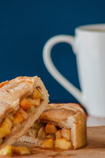 Delicious homemade apple pie slice on a wooden board with a coffee mug in the background.