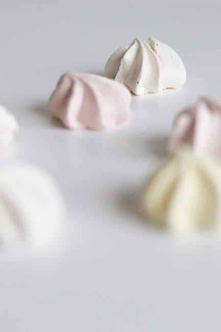 Close-up of pastel meringues on a white surface with soft focus, perfect for food photography.