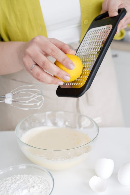 A woman grating lemon zest into cake batter in a modern kitchen setting. Perfect for culinary themes.