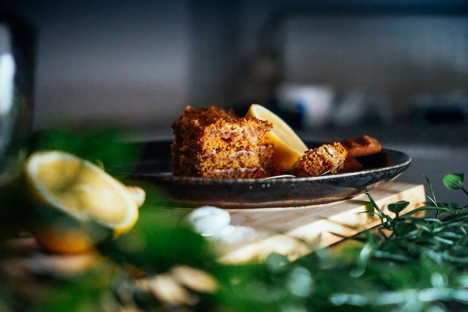 Close-up of lemon cake slice on a plate with fresh ingredients, showcasing natural light and texture.