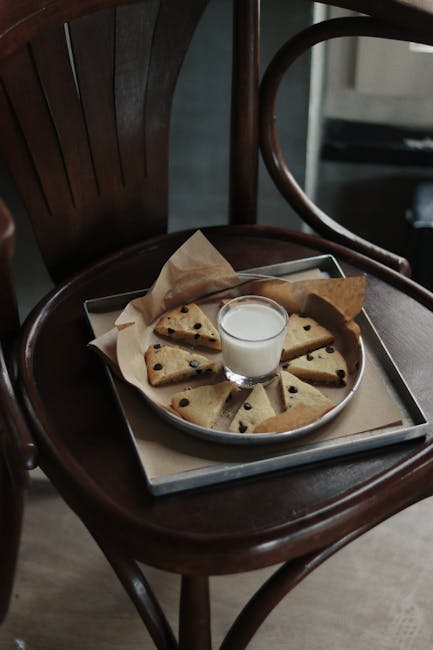 Delicious homemade chocolate chip cookies paired with a glass of milk on a rustic chair.