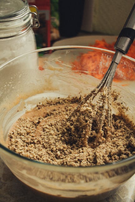 A close-up of dessert preparation with a whisk in a mixing bowl, showcasing textured ingredients.
